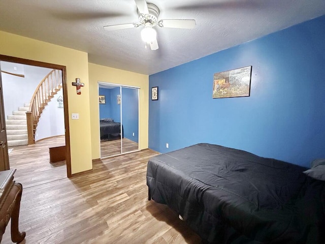 bedroom with a closet, ceiling fan, a textured ceiling, and wood finished floors