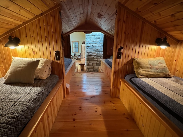 bedroom with wooden walls, wood ceiling, vaulted ceiling, and light wood-style flooring