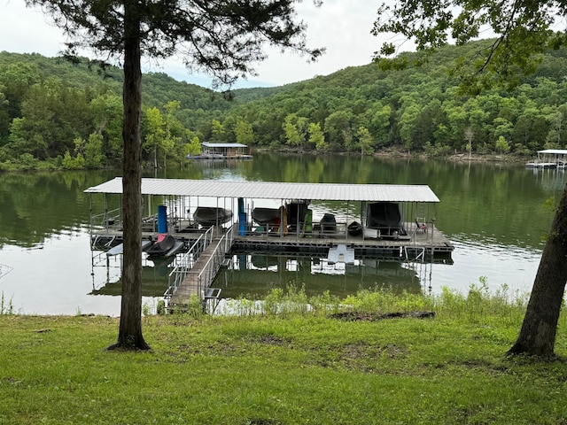 view of dock featuring a water view, a forest view, and boat lift