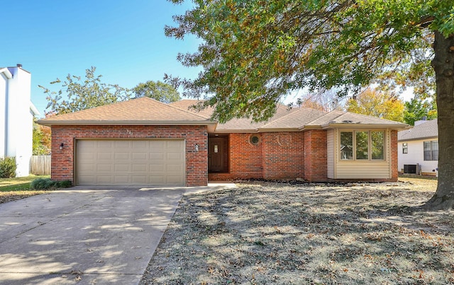 ranch-style house with brick siding, central air condition unit, a shingled roof, a garage, and driveway