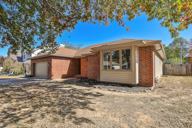 ranch-style house featuring a garage, driveway, brick siding, and fence