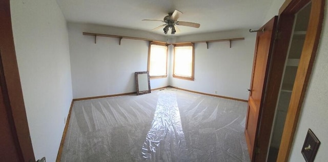 unfurnished room featuring a ceiling fan, light colored carpet, and baseboards