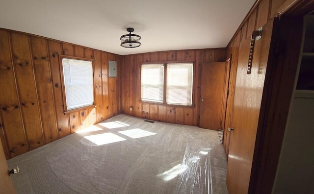 empty room with light carpet, wood walls, and visible vents