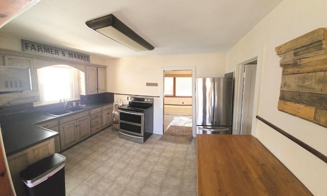 kitchen with dark countertops, light floors, stainless steel appliances, and a sink