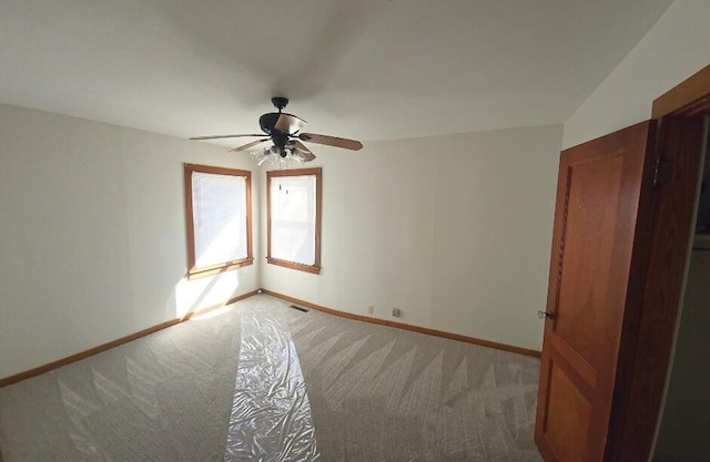 empty room with baseboards, a ceiling fan, and light colored carpet