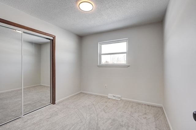 503 Chestnut St, Neosho, MO 64850 - unfurnished bedroom with a textured ceiling, light carpet, visible vents, baseboards, and a closet