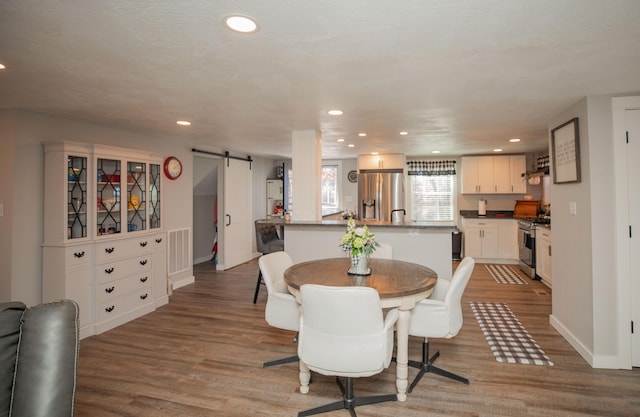 dining room with a barn door, wood finished floors, and recessed lighting