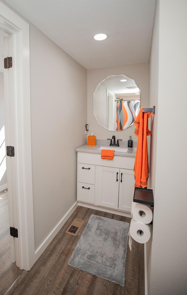 bathroom featuring visible vents, baseboards, wood finished floors, and vanity