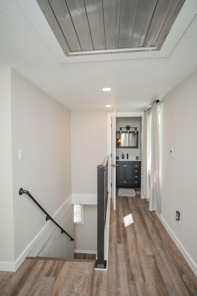 hall featuring dark wood-type flooring, an upstairs landing, and baseboards