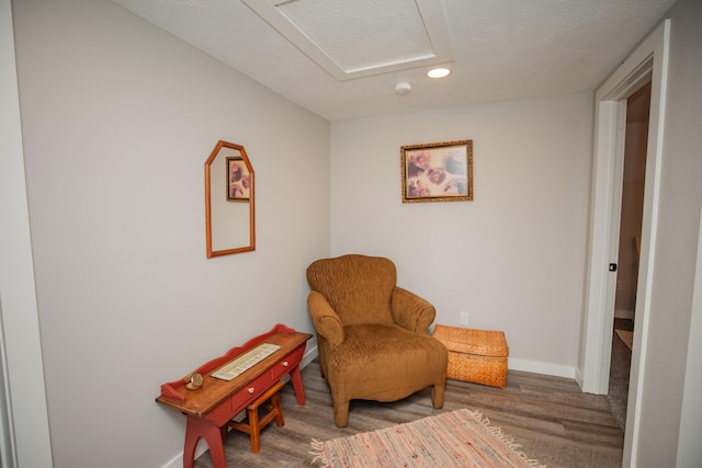 living area featuring wood finished floors, attic access, and baseboards