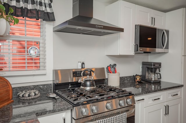 kitchen with stainless steel appliances, range hood, white cabinets, and dark stone countertops