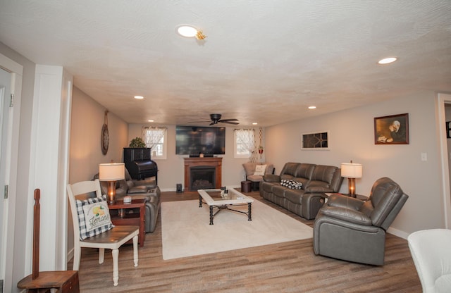 living area featuring recessed lighting, a fireplace, and wood finished floors