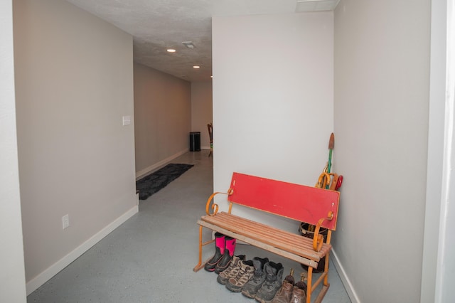 hall featuring finished concrete flooring, baseboards, and recessed lighting