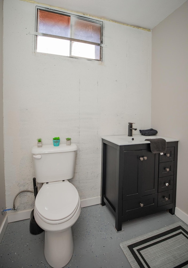 bathroom featuring toilet, baseboards, vanity, and concrete flooring