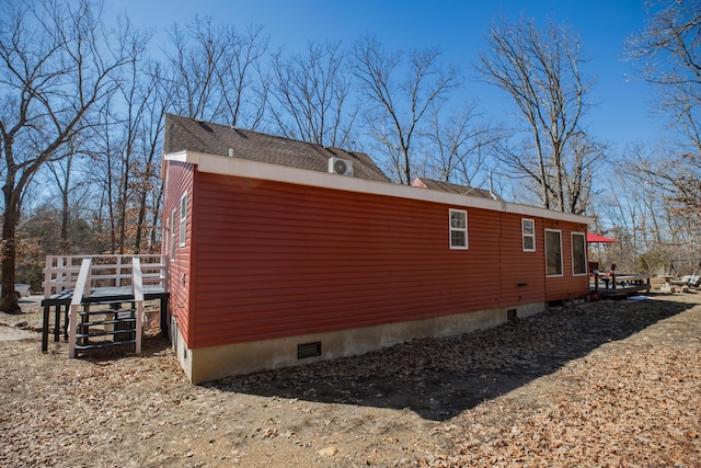 view of side of property featuring crawl space and roof with shingles