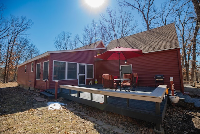 back of house with roof with shingles, a wooden deck, and a sunroom