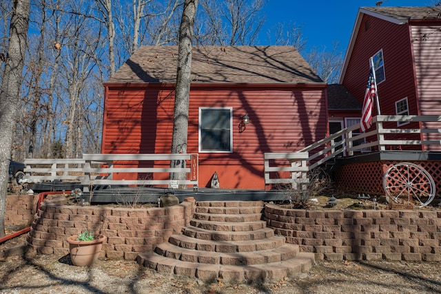 rear view of house with roof with shingles, stairway, and a wooden deck