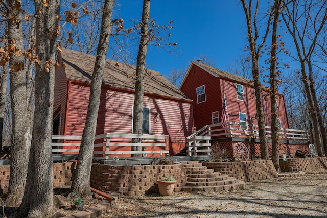 exterior space with roof with shingles, stairs, faux log siding, and a wooden deck