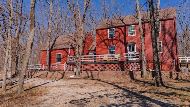 back of house with roof with shingles and a wooden deck