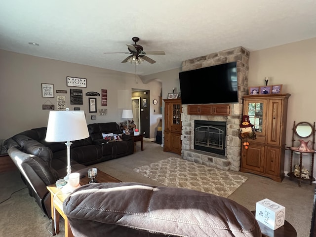 living room with a ceiling fan, light colored carpet, and a fireplace