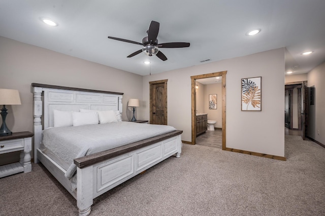 bedroom with recessed lighting, baseboards, light carpet, and ensuite bath