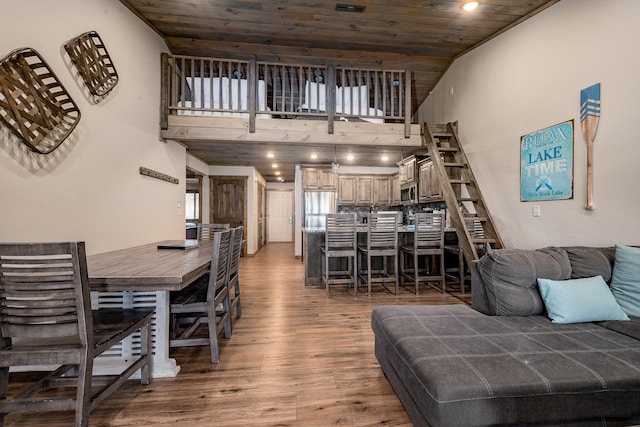 living area with wood ceiling, a high ceiling, and light wood-style floors