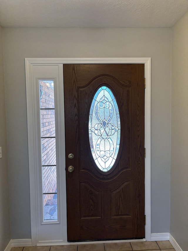 foyer entrance with light tile patterned floors, a wealth of natural light, and baseboards