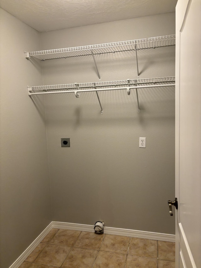 clothes washing area featuring laundry area, electric dryer hookup, baseboards, and light tile patterned floors