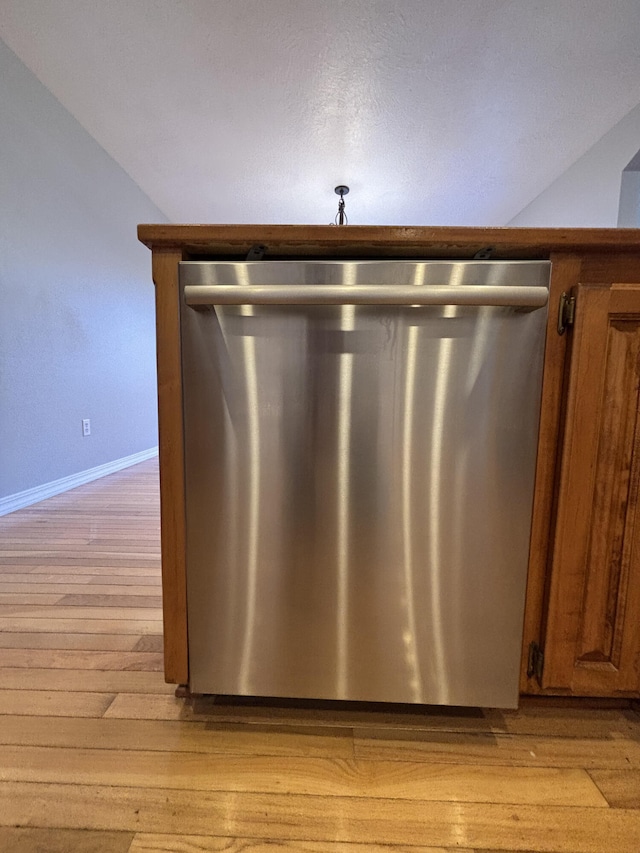 interior details with light wood finished floors, baseboards, brown cabinets, and dishwasher