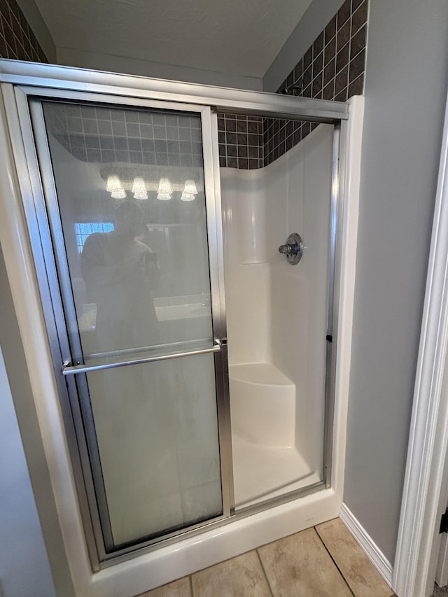 bathroom with a shower stall and tile patterned floors