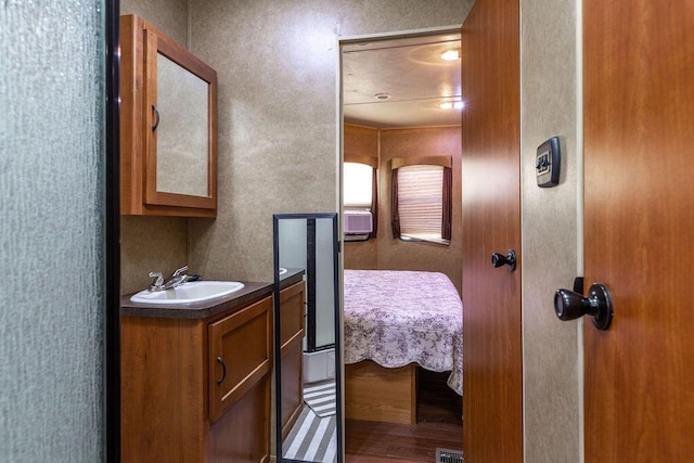 ensuite bathroom with ensuite bath, wood finished floors, and vanity