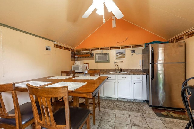 kitchen with white microwave, freestanding refrigerator, vaulted ceiling, white cabinetry, and a sink