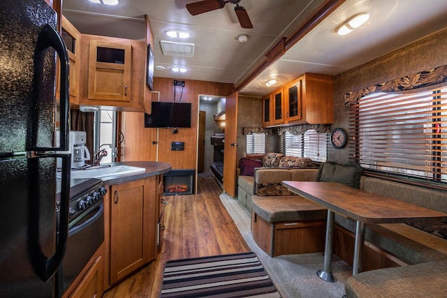 kitchen with black appliances, a sink, glass insert cabinets, and brown cabinets