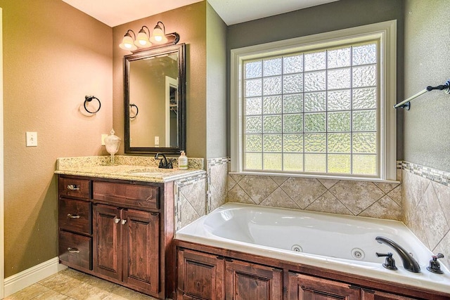 full bathroom featuring a tub with jets, plenty of natural light, and vanity