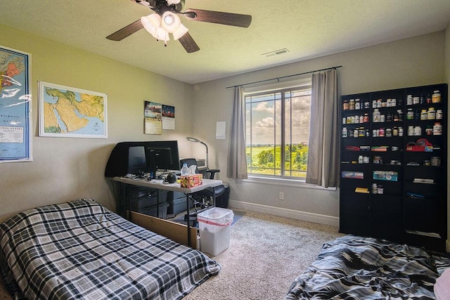 carpeted bedroom featuring baseboards, a textured ceiling, visible vents, and a ceiling fan