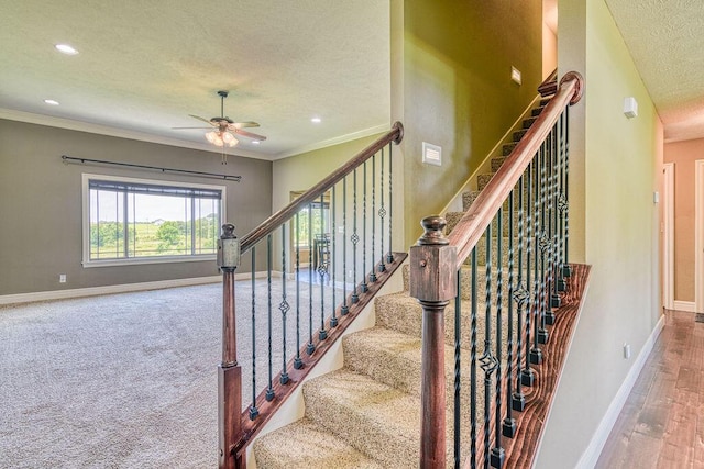 stairs featuring a ceiling fan, crown molding, baseboards, and a textured ceiling