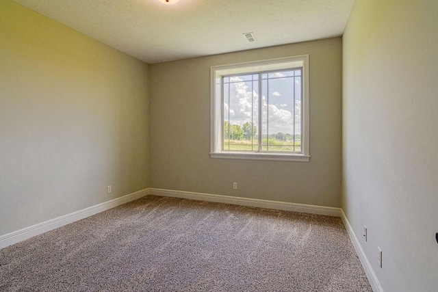 spare room with a textured ceiling, carpet flooring, visible vents, and baseboards