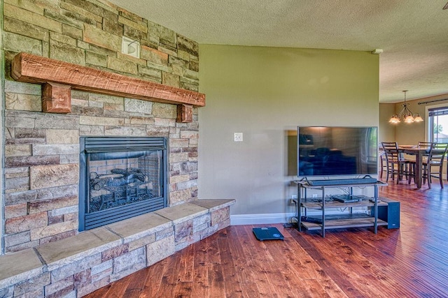 living room featuring dark wood-style floors, a chandelier, a fireplace, and a textured ceiling