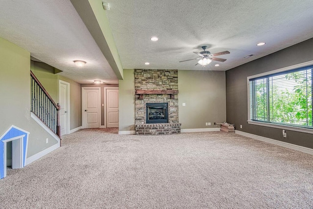 unfurnished living room featuring baseboards, stairway, carpet flooring, and a stone fireplace