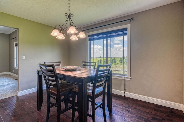 dining room with baseboards, dark wood-style floors, ornamental molding, an inviting chandelier, and a textured ceiling