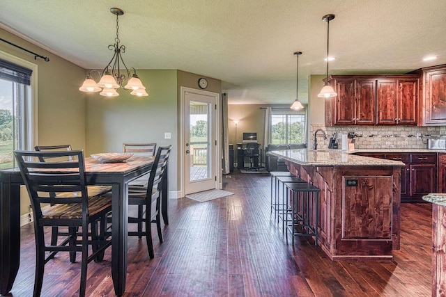 dining space with a notable chandelier, dark wood finished floors, a textured ceiling, and baseboards