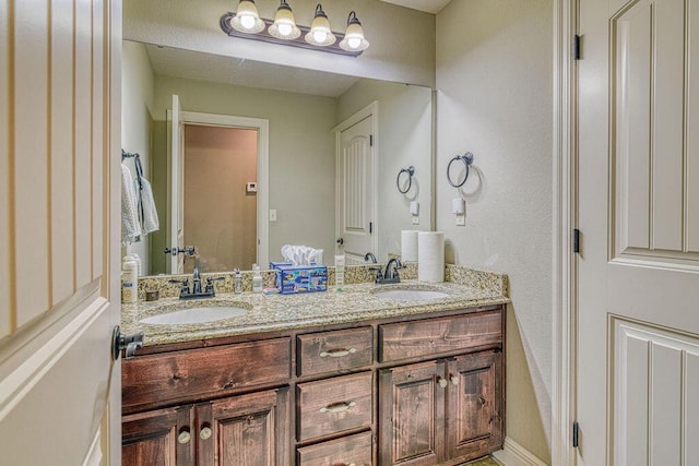 bathroom with double vanity, a sink, and baseboards