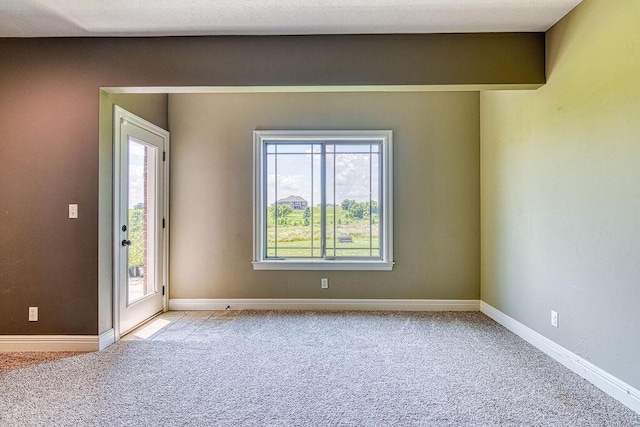 spare room featuring light carpet and baseboards