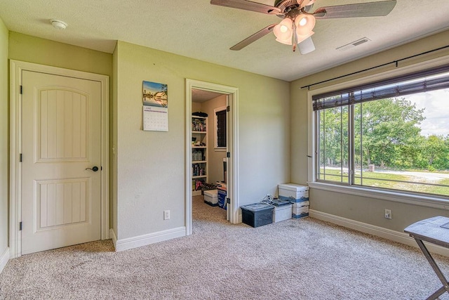 interior space with visible vents, light carpet, a textured ceiling, and a spacious closet