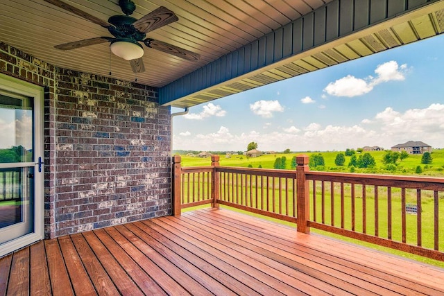 wooden terrace with a ceiling fan and a yard