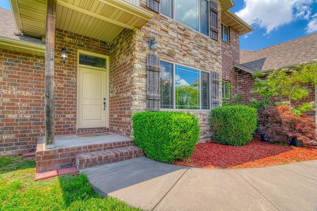 entrance to property with brick siding and a shingled roof