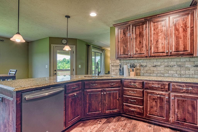 kitchen with a peninsula, light wood-style floors, hanging light fixtures, light stone countertops, and dishwasher