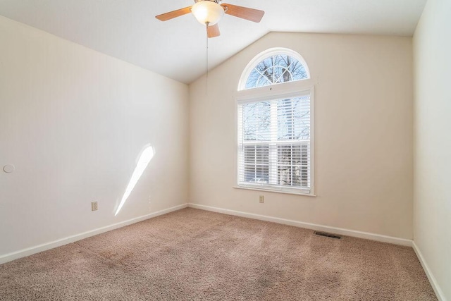 carpeted spare room featuring ceiling fan, visible vents, vaulted ceiling, and baseboards