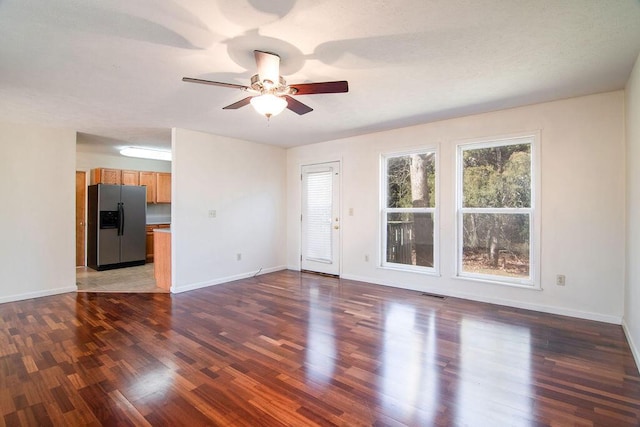 unfurnished living room with ceiling fan, dark wood finished floors, visible vents, and baseboards