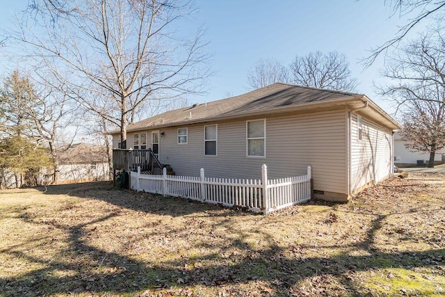 back of house featuring a yard, crawl space, and fence